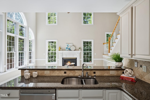 5940 Dahlberg Dr, Raleigh, NC 27603 - kitchen with dishwasher, tasteful backsplash, dark stone counters, a towering ceiling, and white cabinets
