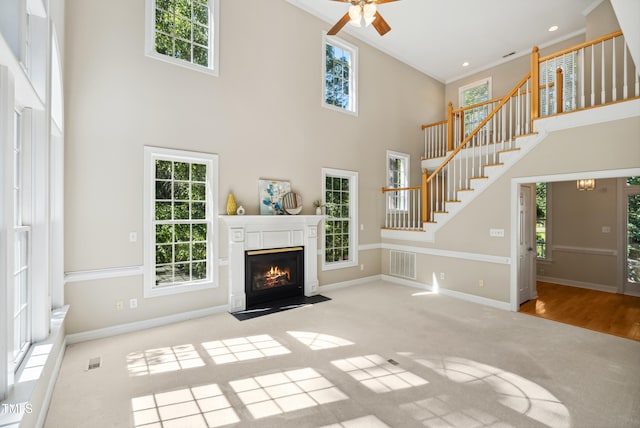 5940 Dahlberg Dr, Raleigh, NC 27603 - unfurnished living room with a towering ceiling, stairway, healthy amount of natural light, carpet floors, and a ceiling fan