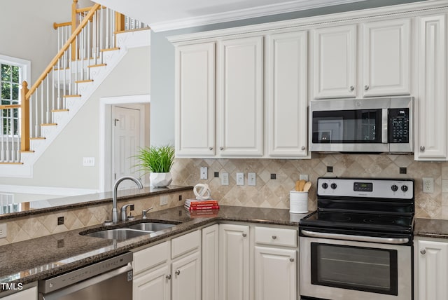 5940 Dahlberg Dr, Raleigh, NC 27603 - kitchen with appliances with stainless steel finishes, decorative backsplash, white cabinetry, dark stone countertops, and crown molding