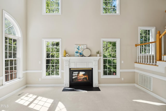 5940 Dahlberg Dr, Raleigh, NC 27603 - unfurnished living room with a high ceiling, a multi sided fireplace, carpet flooring, and stairway