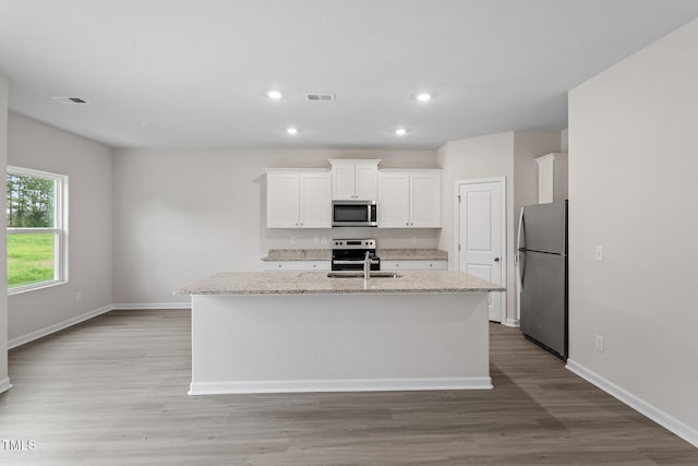 3870 Origin Dr, Bailey, NC 27807 - kitchen featuring stainless steel appliances, white cabinetry, a kitchen island with sink, light wood-style flooring, and light stone countertops