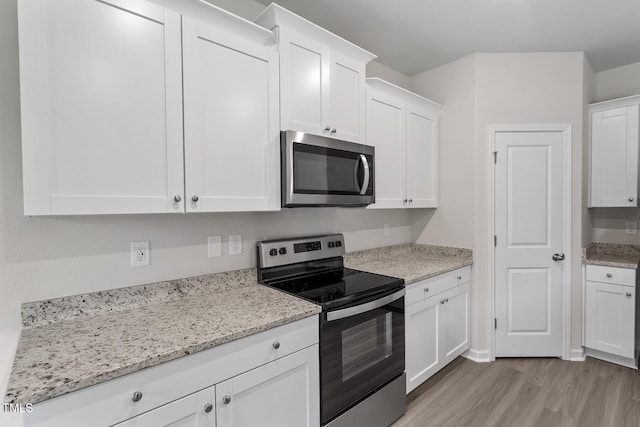 3870 Origin Dr, Bailey, NC 27807 - kitchen with appliances with stainless steel finishes, light wood-type flooring, white cabinets, and light stone counters