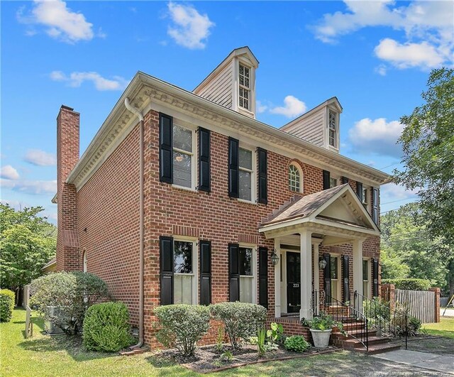 223 Devane St, Fayetteville, NC 28305 - georgian-style home featuring brick siding, a chimney, and a front yard