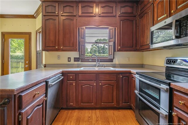 223 Devane St, Fayetteville, NC 28305 - kitchen featuring appliances with stainless steel finishes, ornamental molding, a peninsula, light countertops, and light wood-type flooring