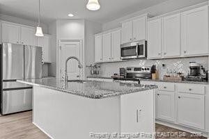 360 Carolina Church Rd, Saint Paul, NC 28384 - kitchen with stainless steel appliances, a center island with sink, white cabinets, hanging light fixtures, and recessed lighting
