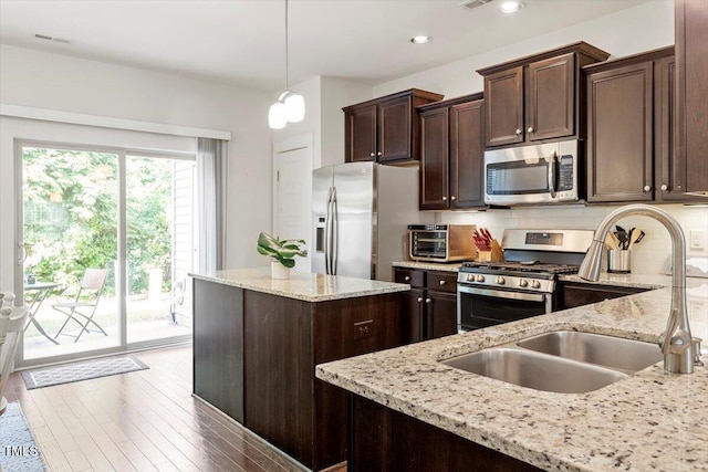 7879 Allscott Way, Raleigh, NC 27612 - kitchen with appliances with stainless steel finishes, dark brown cabinetry, light stone counters, backsplash, and decorative light fixtures