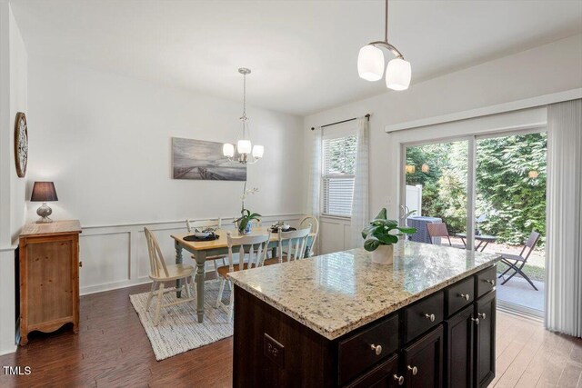 7879 Allscott Way, Raleigh, NC 27612 - kitchen featuring wood finished floors, light stone countertops, pendant lighting, a wainscoted wall, and a chandelier