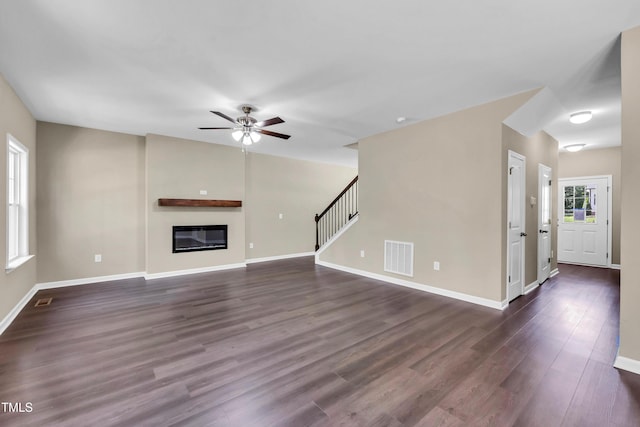 3013 Wesley Farm Ln, Sophia, NC 27350 - unfurnished living room featuring a ceiling fan, a glass covered fireplace, dark wood-type flooring, and stairs
