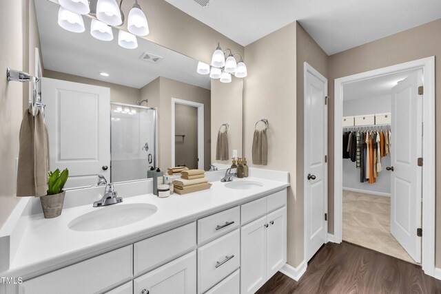 3013 Wesley Farm Ln, Sophia, NC 27350 - bathroom with a stall shower, double vanity, a spacious closet, and wood finished floors