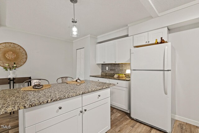 7002 Longstreet Dr Unit C, Raleigh, NC 27615 - kitchen with freestanding refrigerator, tasteful backsplash, white cabinetry, light stone countertops, and light wood-style floors