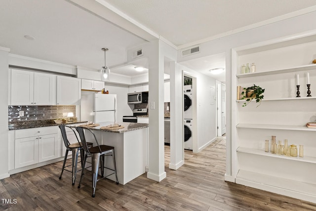 7002 Longstreet Dr Unit C, Raleigh, NC 27615 - kitchen featuring appliances with stainless steel finishes, stacked washing machine and dryer, backsplash, dark stone counters, and dark wood-style flooring