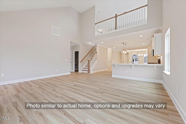 5428 Jaeger Dr Lot # 45, Graham, NC 27253 - unfurnished living room featuring stairway, light wood finished floors, high vaulted ceiling, and a chandelier