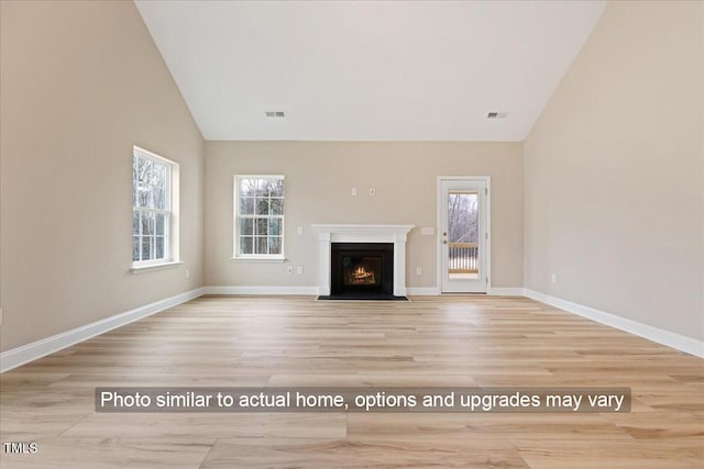 5428 Jaeger Dr Lot # 45, Graham, NC 27253 - unfurnished living room featuring healthy amount of natural light, wood finished floors, a fireplace with flush hearth, and high vaulted ceiling
