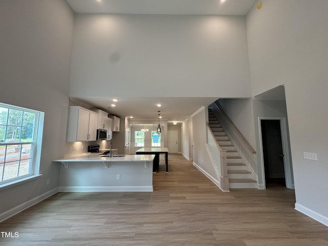 5428 Jaeger Dr Lot # 45, Graham, NC 27253 - kitchen featuring a high ceiling, light countertops, light wood-style flooring, a peninsula, and a kitchen breakfast bar