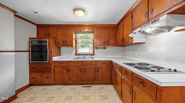 3701 Oak Grove Church Rd, Mebane, NC 27302 - kitchen with stainless steel cooktop, black oven, under cabinet range hood, brown cabinetry, and light countertops