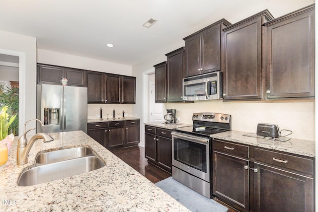 1726 Rapids Ct, Franklinton, NC 27525 - kitchen with appliances with stainless steel finishes, dark wood finished floors, dark brown cabinetry, light stone counters, and recessed lighting