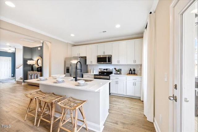 547 Forestville Rd, Wake Forest, NC 27587 - kitchen featuring stainless steel appliances, a kitchen breakfast bar, white cabinetry, light wood-type flooring, and tasteful backsplash
