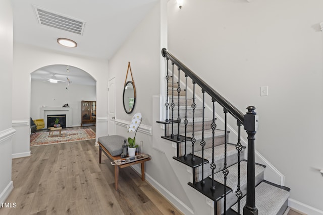 274 Marsh Creek Dr, Garner, NC 27529 - stairway featuring wood finished floors, a fireplace, arched walkways, and a ceiling fan