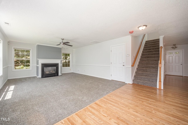 709 Woodgreen Dr, Durham, NC 27704 - unfurnished living room featuring a ceiling fan, stairway, a fireplace with flush hearth, wood finished floors, and a textured ceiling