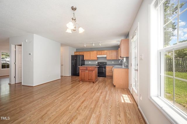 709 Woodgreen Dr, Durham, NC 27704 - kitchen with black appliances, under cabinet range hood, a chandelier, light wood-style flooring, and plenty of natural light
