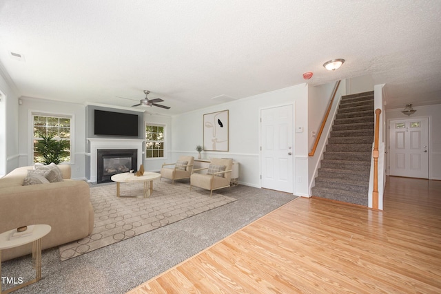 709 Woodgreen Dr, Durham, NC 27704 - living area with wood finished floors, a ceiling fan, stairway, a fireplace with flush hearth, and crown molding