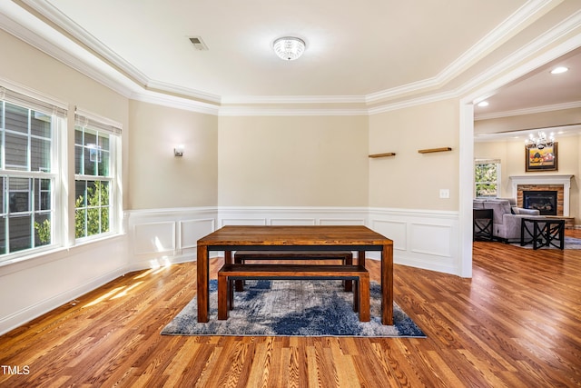 2129 Glade Valley Ln, Morrisville, NC 27560 - dining area featuring wood finished floors, ornamental molding, a fireplace, wainscoting, and a decorative wall