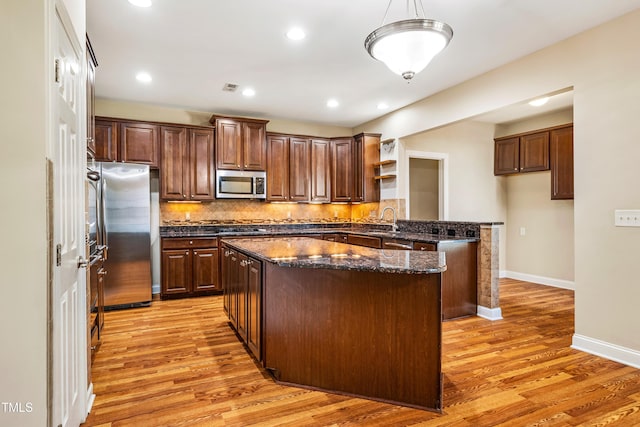 2129 Glade Valley Ln, Morrisville, NC 27560 - kitchen with appliances with stainless steel finishes, open shelves, a center island, light wood-style floors, and tasteful backsplash