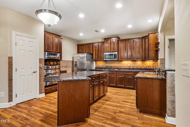 2129 Glade Valley Ln, Morrisville, NC 27560 - kitchen with appliances with stainless steel finishes, light wood-type flooring, a kitchen island, dark stone countertops, and recessed lighting