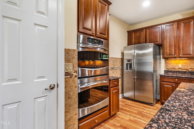 2129 Glade Valley Ln, Morrisville, NC 27560 - kitchen with stainless steel appliances, light wood-style flooring, dark stone countertops, and tasteful backsplash