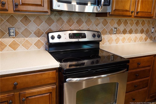 3310 Starboard Way Unit 301, Fayetteville, NC 28314 - kitchen with stainless steel appliances, brown cabinetry, light countertops, and backsplash
