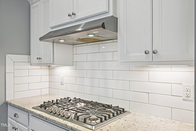 833 Atticus Way, Durham, NC 27703 - kitchen with under cabinet range hood, stainless steel gas cooktop, white cabinetry, decorative backsplash, and light stone countertops