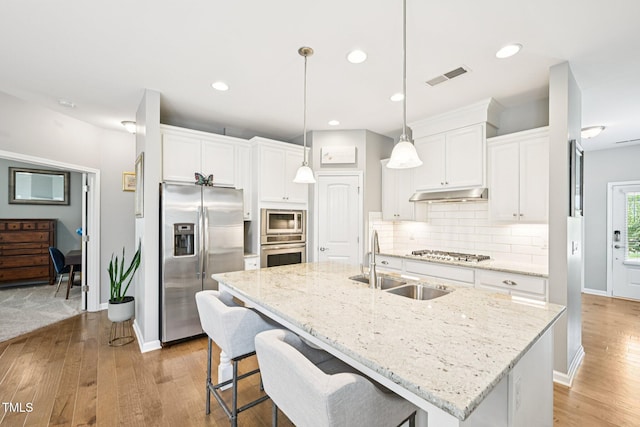 833 Atticus Way, Durham, NC 27703 - kitchen featuring appliances with stainless steel finishes, light wood-type flooring, under cabinet range hood, backsplash, and white cabinets