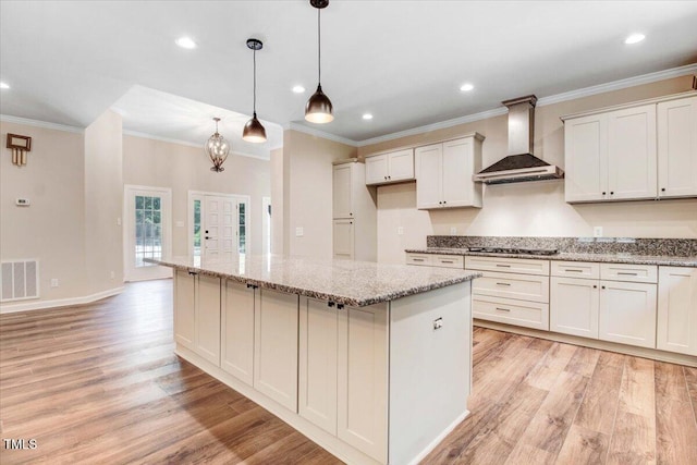 206 Tramway Pl, Goldsboro, NC 27534 - kitchen with wall chimney range hood, light wood finished floors, crown molding, a center island, and light stone counters