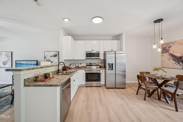 3973 Volkswalk Pl, Raleigh, NC 27610 - kitchen with appliances with stainless steel finishes, light wood finished floors, decorative backsplash, white cabinets, and a peninsula