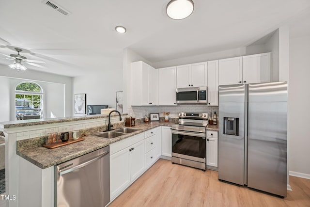 3973 Volkswalk Pl, Raleigh, NC 27610 - kitchen with stainless steel appliances, a peninsula, light wood-type flooring, white cabinetry, and recessed lighting