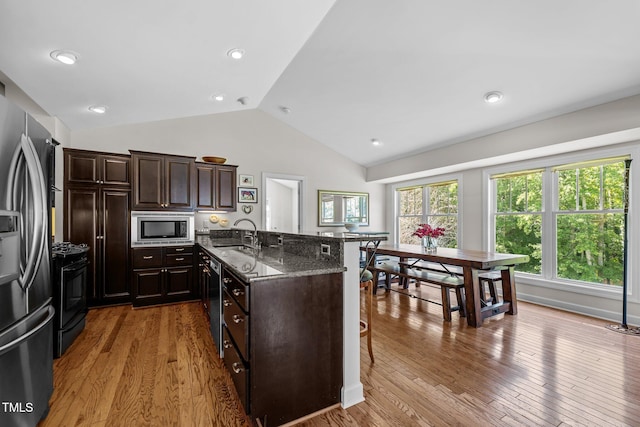 3511 Corbett Rd, Mebane, NC 27302 - kitchen featuring stainless steel appliances, lofted ceiling, light wood finished floors, dark stone countertops, and a breakfast bar area