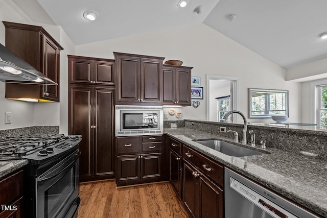 3511 Corbett Rd, Mebane, NC 27302 - kitchen featuring appliances with stainless steel finishes, lofted ceiling, wall chimney range hood, light wood-style flooring, and dark stone counters