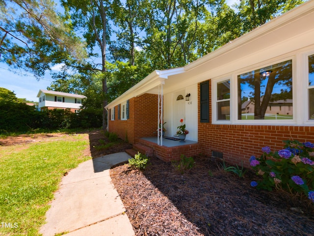 438 N Hickory St, Angier, NC 27501 - view of exterior entry with brick siding, crawl space, a lawn, and covered porch