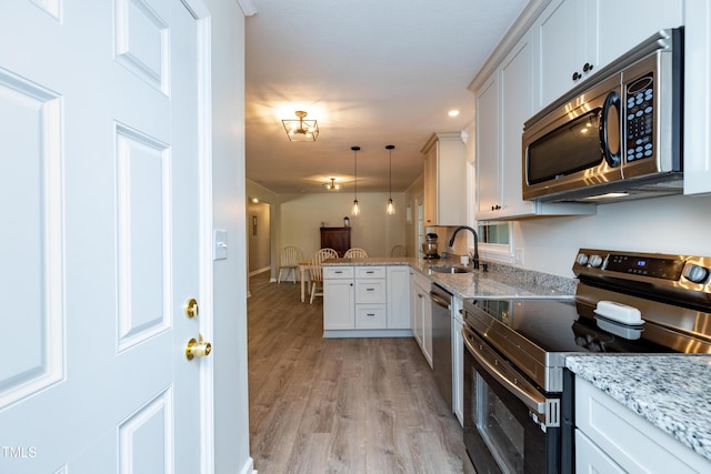438 N Hickory St, Angier, NC 27501 - kitchen featuring appliances with stainless steel finishes, light wood-type flooring, a peninsula, white cabinets, and pendant lighting
