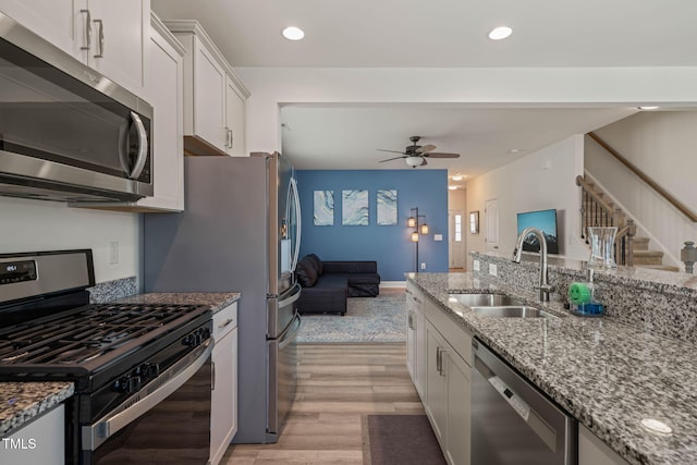 1137 Amber Shadow Dr, Durham, NC 27703 - kitchen with appliances with stainless steel finishes, light wood-style floors, ceiling fan, light stone counters, and white cabinetry