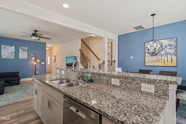 1137 Amber Shadow Dr, Durham, NC 27703 - kitchen with stainless steel dishwasher, open floor plan, light wood-style floors, a center island with sink, and white cabinetry