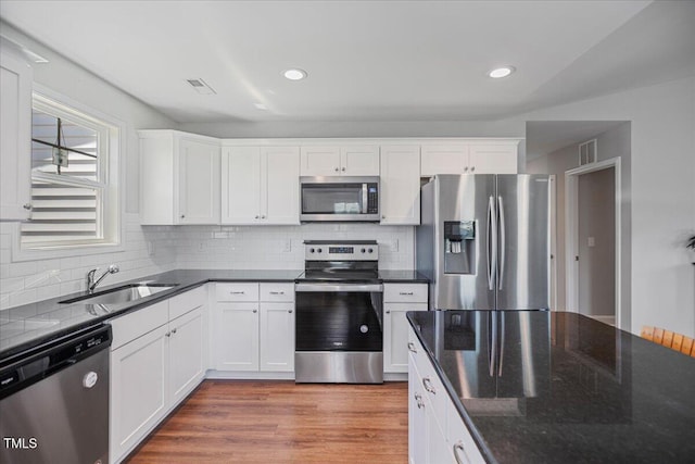 174 Arrow Ln, Middlesex, NC 27557 - kitchen featuring appliances with stainless steel finishes, white cabinets, tasteful backsplash, light wood-style flooring, and recessed lighting