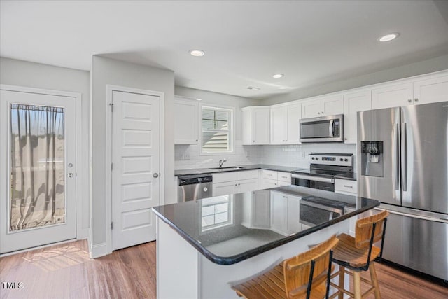 174 Arrow Ln, Middlesex, NC 27557 - kitchen featuring appliances with stainless steel finishes, a kitchen bar, decorative backsplash, white cabinetry, and recessed lighting