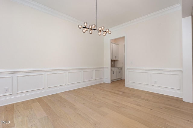 1417 Westmoreland Dr, Raleigh, NC 27612 - unfurnished dining area featuring ornamental molding, a chandelier, light wood-style floors, a wainscoted wall, and a decorative wall