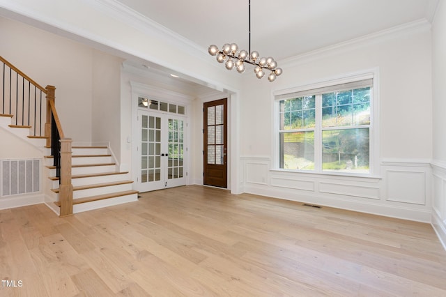 1417 Westmoreland Dr, Raleigh, NC 27612 - unfurnished dining area featuring french doors, crown molding, stairway, light wood-style flooring, and a wainscoted wall