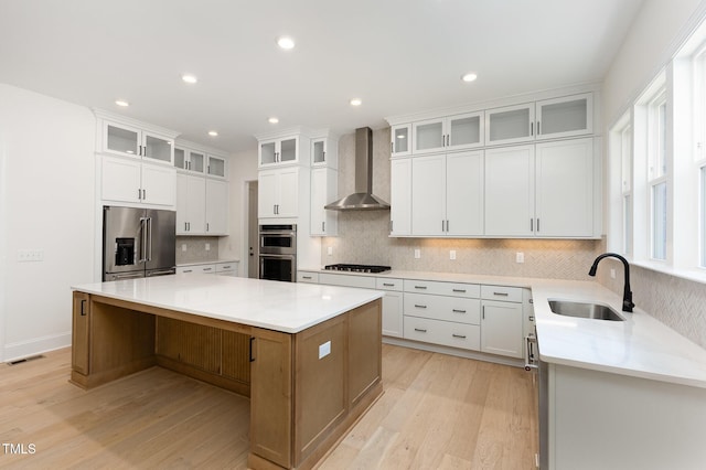 1417 Westmoreland Dr, Raleigh, NC 27612 - kitchen with stainless steel appliances, wall chimney exhaust hood, light wood-type flooring, a center island, and decorative backsplash