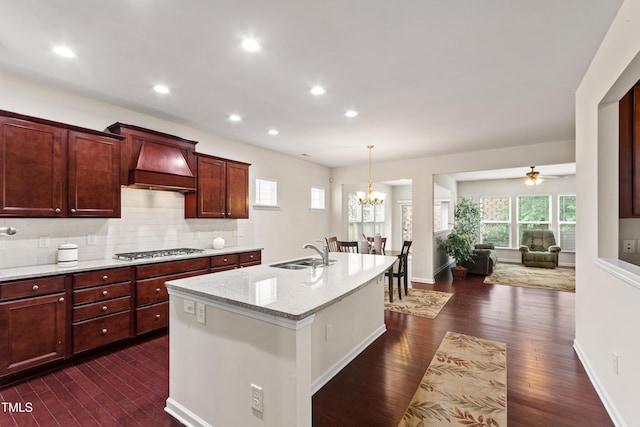 1320 Cozy Oak Ave, Cary, NC 27519 - kitchen featuring premium range hood, stainless steel gas stovetop, dark wood-style flooring, an island with sink, and tasteful backsplash