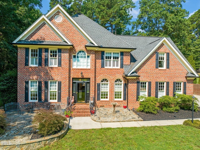 9009 Hometown Dr, Raleigh, NC 27615 - colonial-style house featuring brick siding, a shingled roof, and a front yard