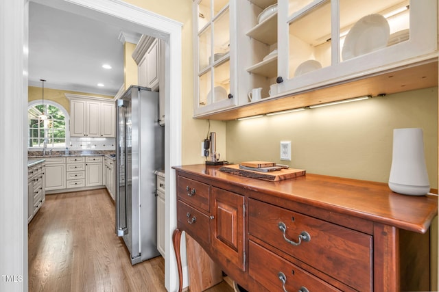 9009 Hometown Dr, Raleigh, NC 27615 - kitchen with freestanding refrigerator, light wood finished floors, glass insert cabinets, hanging light fixtures, and recessed lighting