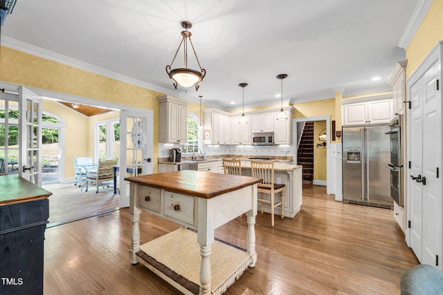 9009 Hometown Dr, Raleigh, NC 27615 - kitchen featuring appliances with stainless steel finishes, wooden counters, a center island, crown molding, and light wood-style flooring